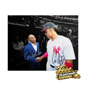 Puede incluir: Una fotograf&iacute;a que muestra a una persona con traje azul estrechando la mano de una persona con una camiseta de b&eacute;isbol a rayas blancas con un logotipo rosa y mu&ntilde;equeras rosas. Ambas personas tienen firmas en la imagen. El fondo muestra un estadio.
