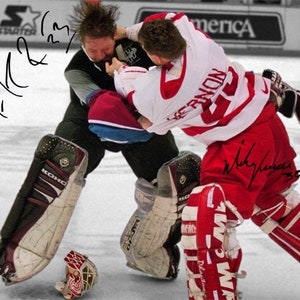May include: A black and white photograph of two hockey players in a fight. The player in the red jersey is on top of the player in the black jersey. The player in the red jersey has signed the photo "Nicklas Lidstrom 30". The player in the black jersey has signed the photo "Rick DiPietro 29".