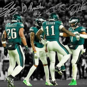 Puede incluir: Cuatro jugadores de fútbol americano con uniformes verdes y blancos, con cascos, están juntos en un campo. Los jugadores llevan los números 26, 11 y 1. El fondo es una multitud de personas en blanco y negro.