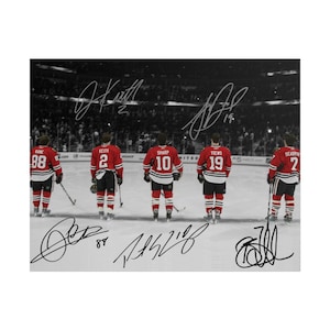 Peut inclure: Une photographie en noir et blanc montrant cinq joueurs de hockey en maillots rouges à rayures noires et blanches, debout sur la glace. Les maillots portent les noms Kane, Keith, Sharp, Toews et Seabrook avec leurs numéros. Inclut des signatures.
