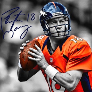 May include: A black and white photo of a football player wearing a blue and orange jersey with the number 18 on it. The player is holding a football and has a signature that says "Peyton 18 Manning" above his head.