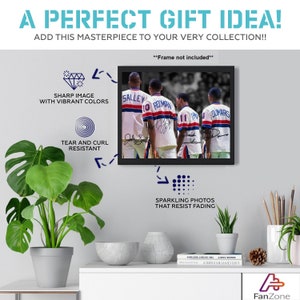Op de afbeelding: Zwart-witfoto van vier voetballers in uniform, met hun ruggen naar de camera. De spelers dragen shirts met de namen "Salley", "Roomman" en "Dunars" op de rug. De foto is ingelijst in een zwart frame.