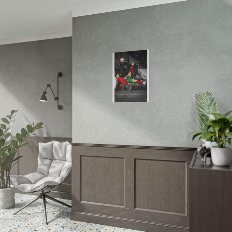May include: A rectangular wall poster featuring a black and white photograph of a footballer in a red jersey and green shorts performing a bicycle kick to strike a football. The player is captured in mid-air against a blurred background.