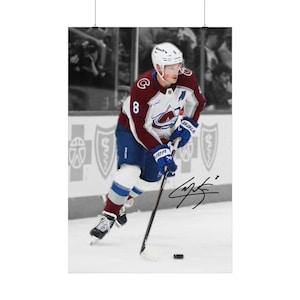 Könnte beinhalten: Ein professioneller Eishockeyspieler in einem weißen, burgunderroten und blauen Trikot mit der Nummer 8, weißem Helm und blauen Handschuhen, der mit einem Eishockeyschläger auf dem Eis läuft. Das Bild zeigt eine schwarze Tintensignatur als Overlay.
