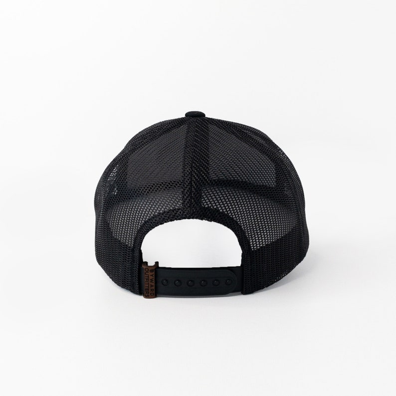 May include: Black mesh trucker hat with a brown leather patch that says "Byward Outfitters".