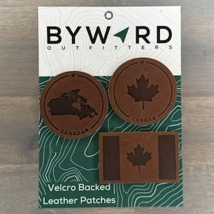 Peut inclure: Trois patchs en cuir marron avec un dos en velcro. Les patchs représentent le drapeau canadien, une carte du Canada et un drapeau canadien avec une bande blanche.