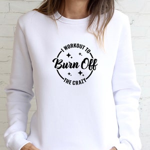 May include: White sweatshirt with a black circle graphic that says "I workout to burn off the crazy" with stars around the text.