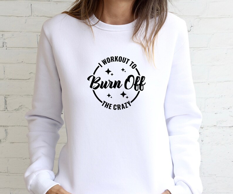May include: White sweatshirt with a black circle graphic that says "I workout to burn off the crazy" with stars around the text.