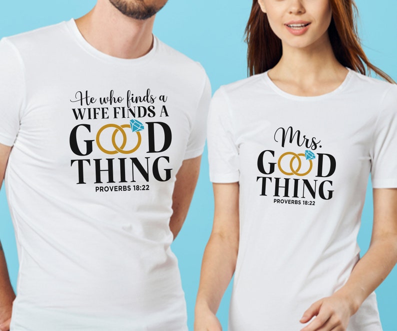 May include: Two white t-shirts with black text and a graphic of two gold rings with a blue diamond. The text on the first shirt reads "He who finds a WIFE FINDS A GOOD THING PROVERBS 18:22". The text on the second shirt reads "Mrs. GOOD THING PROVERBS 18:22".
