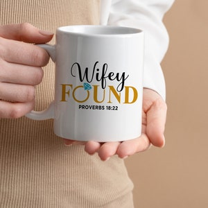 May include: White ceramic mug with a gold inscription that reads "Wifey FOUND Proverbs 18:22". A blue diamond is above the word "FOUND".