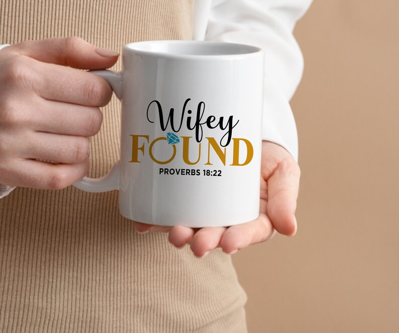 May include: White ceramic mug with a gold inscription that reads "Wifey FOUND Proverbs 18:22". A blue diamond is above the word "FOUND".