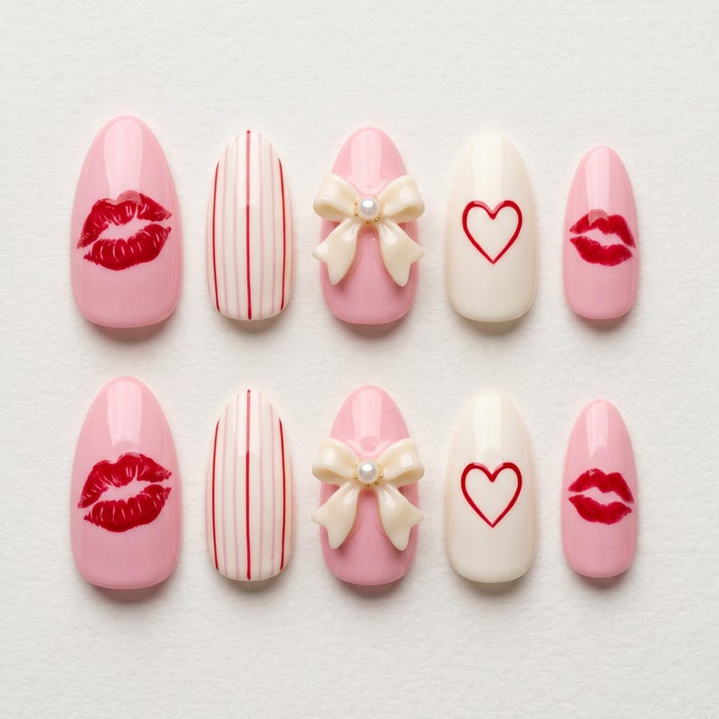 May include: A set of ten artificial nails in various designs. The nails feature pink, white, and cream colors with designs including red lips, a white bow with a pearl, red stripes, and a red heart.