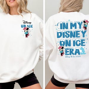 May include: White sweatshirt with a blue and white graphic of Mickey Mouse on ice. The text on the sweatshirt says "Disney On Ice" and "In My Disney On Ice Era".