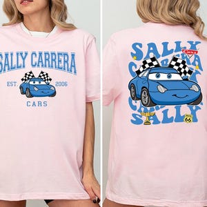 a woman wearing a pink shirt with a blue car on it