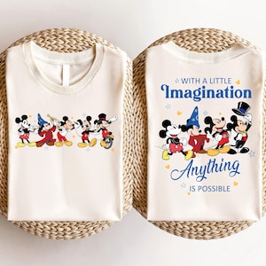 May include: Two white t-shirts with a Mickey Mouse theme. One shirt features a line of Mickey Mouse characters playing music. The other shirt features four Mickey Mouse characters with the text "With a little imagination anything is possible".
