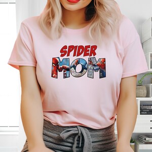 May include: Pink t-shirt with the text "SPIDER MOM" in red letters. The letters are made up of images of Spider-Man.