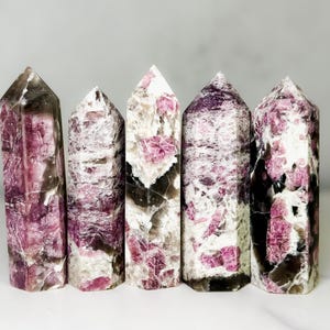 Pu&ograve; includere: Cinque torri di cristallo lucido con una miscela di rosa, bianco e grigio scuro. I cristalli hanno una forma colonnare con cime appuntite. L'estetica generale &egrave; naturale ed elegante, adatta all'arredamento della casa o alle pratiche spirituali.