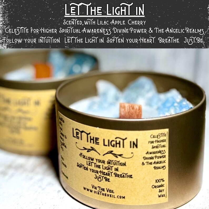 May include: Two gold candle jars with a light blue wax and a wooden wick. The label on the jar reads "Let the Light In" and "Celestite for Higher Spiritual Awareness Divine Power & The Angelic Realms". The label also reads "Follow your intuition. Let the light in. Soften your heart. Breathe. Just be." and "Via The Veil www.viatheveil.com".