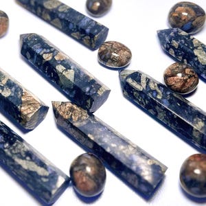 Könnte beinhalten: Eine Sammlung von blauen und braunen Edelstein-Spitzen und Trommelsteinen. Die Spitzen sind lang und schlank, mit einer spitzen Spitze. Die Trommelsteine sind rund und glatt.
