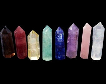 May include: A set of ten crystal points in various colors, including clear, amethyst, rose quartz, blue, green, and brown. The points are arranged in a row on a black background.