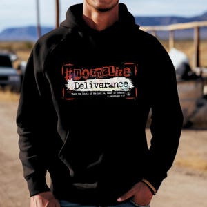 May include: Black hoodie with the text "#normalize Deliverance" in a red and white design. The hoodie also includes the Bible verse 2 Corinthians 3:17. The hoodie is a casual garment.
