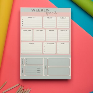 以下が含まれることがあります： ピンクとグレーの週間プランナー。やることリスト、毎日のスケジュール、目標、優先事項、習慣、引用、メモのセクションがあります。