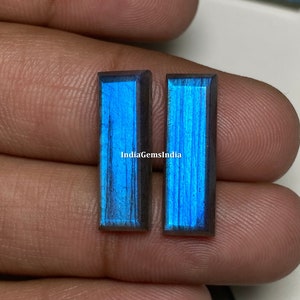 May include: Two rectangular labradorite gemstones with a blue iridescent sheen. The stones are set in a bezel setting and have a polished finish.