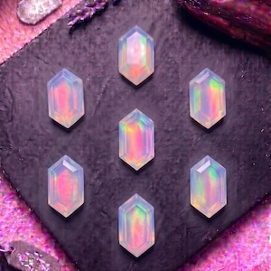 May include: Seven hexagonal, translucent, iridescent cabochons arranged in a symmetrical pattern. Each piece displays a soft, milky white base with shifting pink, orange, and green light reflections, creating a glowing, multi-faceted appearance.