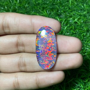 May include: Oval-shaped opal gemstone with a clear base and a colorful, iridescent pattern of red, orange, blue, and green.
