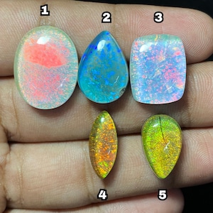 May include: Five polished opal gemstones in various shapes. The opals display a range of colors, including blue, green, orange, and pink. The gemstones are oval, teardrop, and rectangular shapes. The opals are set against a dark background.
