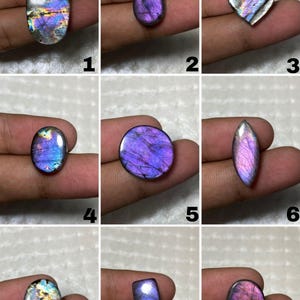 May include: A collection of nine polished labradorite gemstones in various shapes including oval, teardrop, round, marquise, and rectangular. Each stone displays iridescent flashes of purple, blue, and gold, numbered one through nine.