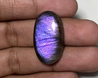 May include: A large oval-shaped labradorite gemstone with a purple and grey iridescent sheen.