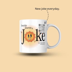 May include: White ceramic mug with the text "Everyday deserves a Joke" and a smiling sun graphic. The mug also features a QR code and the phrase "Especially while the coffee kicks in."