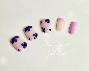 May include: Five short square-shaped fake nails with a pink and white french manicure design. Three of the nails have a floral design with purple and pink flowers.