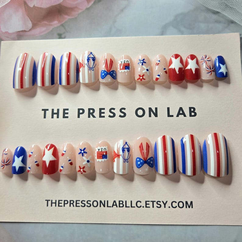Pode incluir: Um conjunto de unhas posti&ccedil;as com tema patri&oacute;tico. Os desenhos incluem listras vermelhas, brancas e azuis, estrelas, la&ccedil;os e gr&aacute;ficos de selos postais. O texto "THE PRESS ON LAB" e "THEPRESSONLABLLC.ETSY.COM" s&atilde;o vis&iacute;veis.