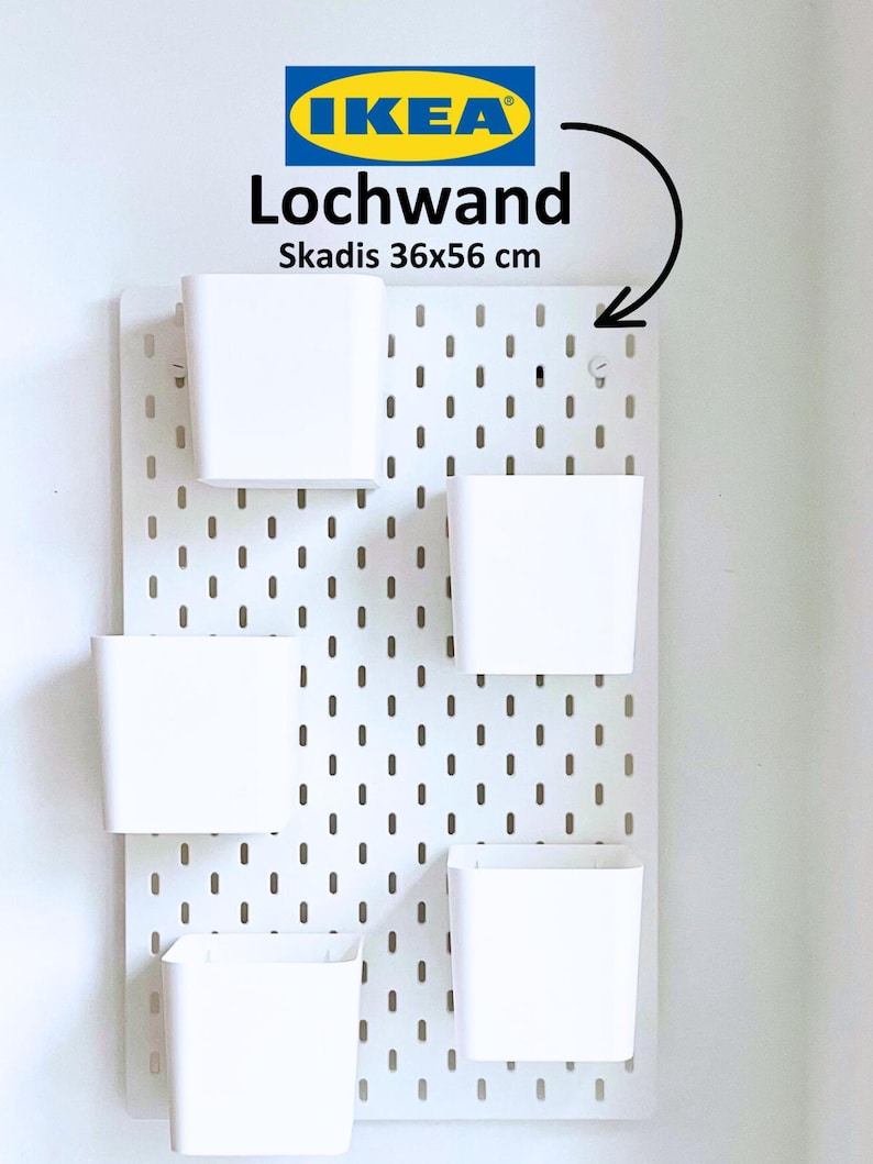May include: White pegboard with the IKEA logo and the text "Lochwand Skadis 36x56 cm". Five white storage bins are attached to the pegboard.