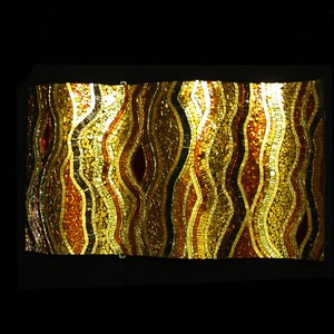 May include: A mosaic wall art piece with a wavy pattern in shades of gold, brown, and red.