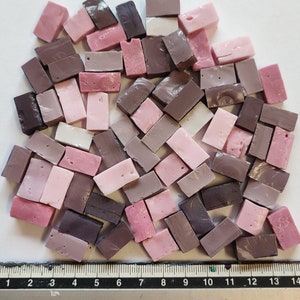 May include: A collection of small, rectangular mosaic tiles in shades of pink and brown. The tiles are arranged in a random pattern and are approximately 1 inch in length.