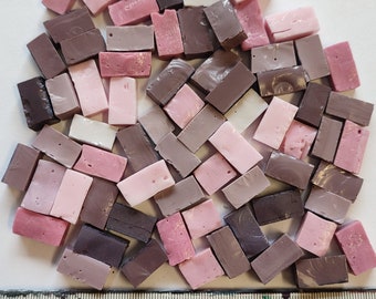 May include: A collection of small, rectangular mosaic tiles in shades of pink and brown. The tiles are arranged in a random pattern and are approximately 1 inch in length.