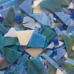 May include: A collection of irregularly shaped glass pieces in shades of blue, teal, and white. The pieces vary in size and shape, creating a mosaic-like appearance. Some pieces have a marbled effect.