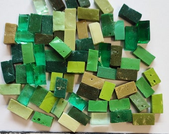 May include: A collection of green, light green, and dark green glass mosaic tiles. The tiles are rectangular and have a variety of sizes.