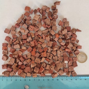 以下が含まれることがあります： 赤い正方形のモザイクタイルの大きな山。タイルはランダムなパターンで配置されており、定規で測定されています。