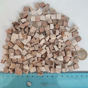 以下が含まれることがあります： 薄い茶色とピンクの小さな不規則な大理石のタイルの山。タイルはランダムなパターンで配置されており、サイズは約1.2cmです。