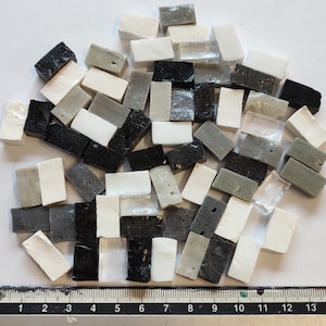 Puede incluir: Una colección de pequeñas baldosas de mosaico rectangulares en varios tonos de gris, negro y blanco. Las baldosas están dispuestas en un patrón aleatorio.