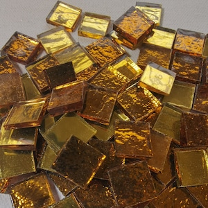 May include: A pile of small, square, gold-colored glass tiles. The tiles have a textured surface and are perfect for crafting projects.