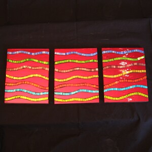 May include: Three rectangular wall art pieces with a red background and wavy lines of different colors, including blue, green, yellow, and brown.