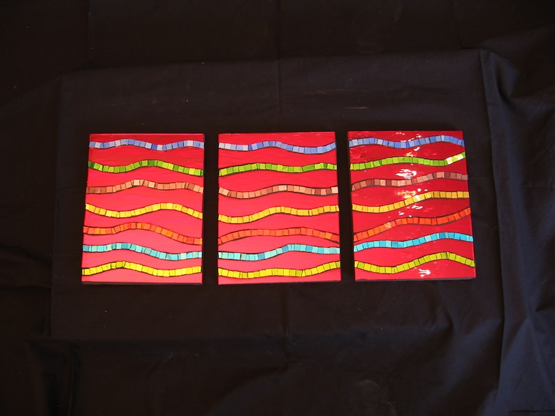 May include: Three rectangular wall art pieces with a red background and wavy lines of different colors, including blue, green, yellow, and brown.