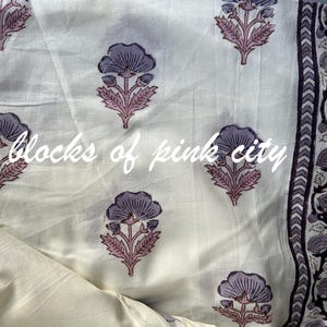 Może przedstawiać: Biały materiał z fioletowym nadrukiem kwiatowym. Materiał ma obwódkę z powtarzającym się wzorem fioletowych kwiatów i liści. Na materiale nadrukowany jest tekst "blocks of pink city".