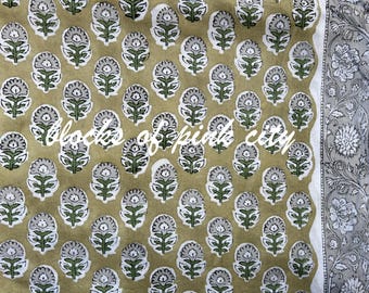 May include: A close-up of a fabric with a repeating pattern of small, gray and white flowers on a light brown background. The fabric has a white border with a floral design.