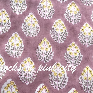 Könnte beinhalten: Ein rosa Stoff mit einem sich wiederholenden Muster aus gelben Blumen und grauen Blättern. Der Stoff hat einen dezenten, verblassten Look.